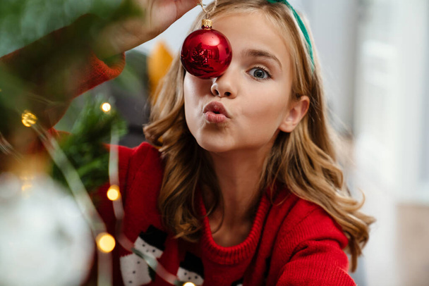 Close up portrait of a pretty girl at christmas time, holding christmas decorations, close up - Photo, Image