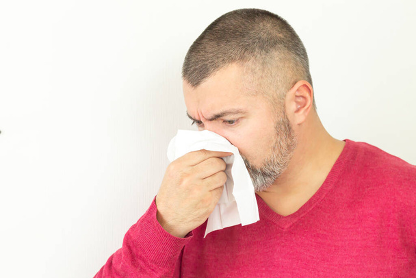 Man holding paper handkerchief and sneezing on white background - Photo, Image