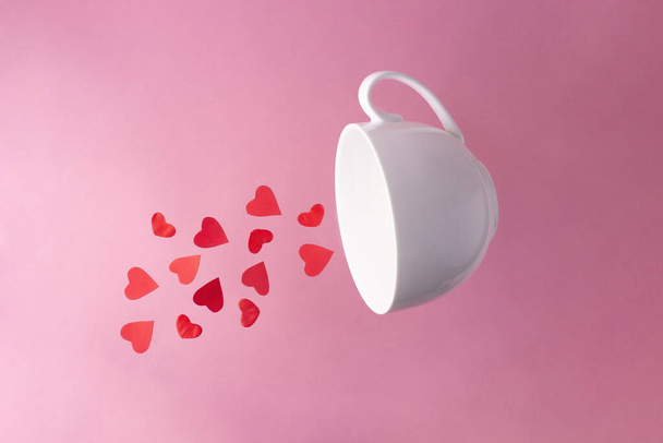 Red hearts flying out of a white cup on a pink background, close up. Valentine's Day card. - Zdjęcie, obraz