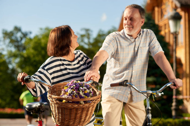 Feliz pareja de ancianos con bicicletas y flores. - Foto, imagen