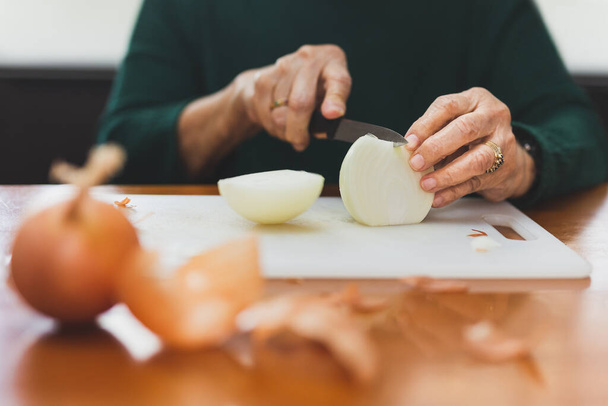 Senior woman hands cut onions with a knife. - Foto, Bild