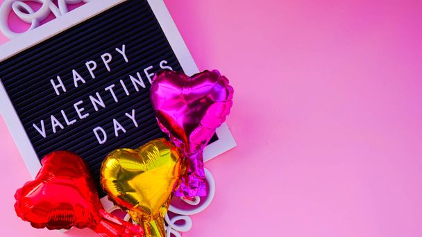 Greeting card for Valentine's Day on a pink background.Foil hearts balloons and chocolates top view of Valentine's Day. Happy Valentine day card or background concept. - Foto, Bild