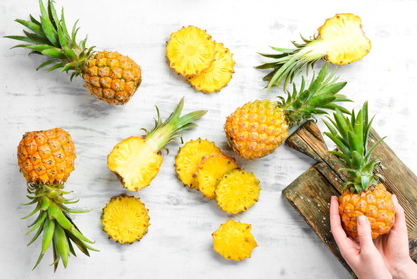 Pineapple collection. Whole and sliced pineapple, on a white wooden background. Top view. Free space for text. - Фото, изображение