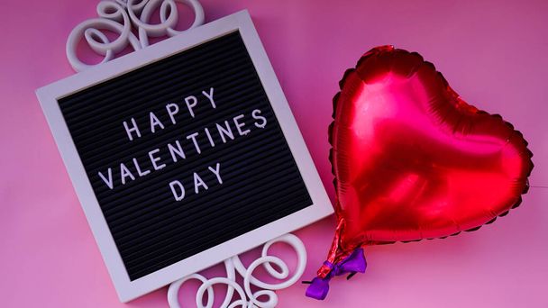 Greeting card for Valentine's Day on a pink background.Foil hearts balloons and chocolates top view of Valentine's Day. Happy Valentine day card or background concept. - Фото, изображение