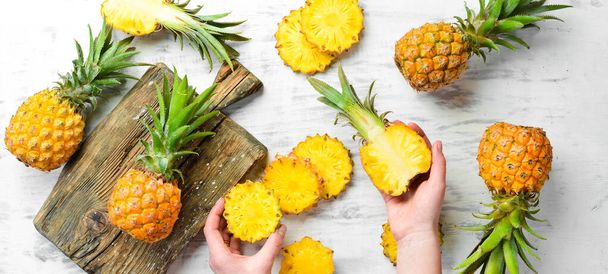 Pineapple collection. Whole and sliced pineapple, on a white wooden background. Top view. Free space for text. - 写真・画像