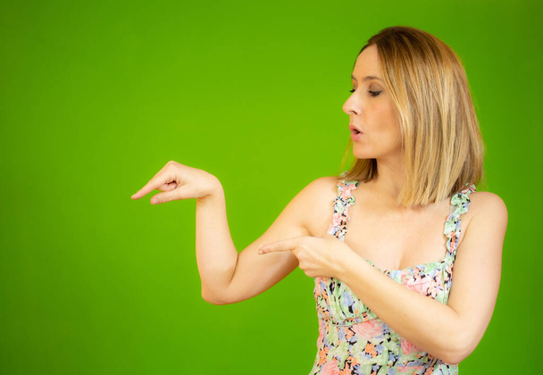 Surprised young woman over isolated green background pointing finger to the side - Foto, immagini