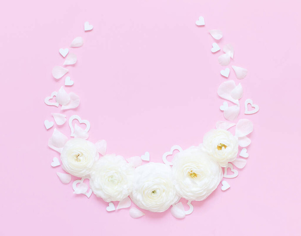 Cirkel frame gemaakt van crème bloemen, bloemblaadjes en hartjes op een licht roze achtergrond bovenaanzicht. Voorjaarsconcept - Foto, afbeelding