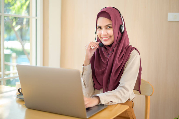 Мусульманська операторка в гарнітурі, використовуючи комп'ютер, що відповідає на дзвінок клієнтів в офісі, концепція обслуговування клієнтів
 - Фото, зображення