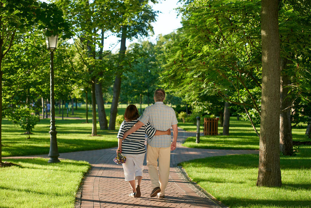 Walking couple in the green summer park. - Фото, зображення