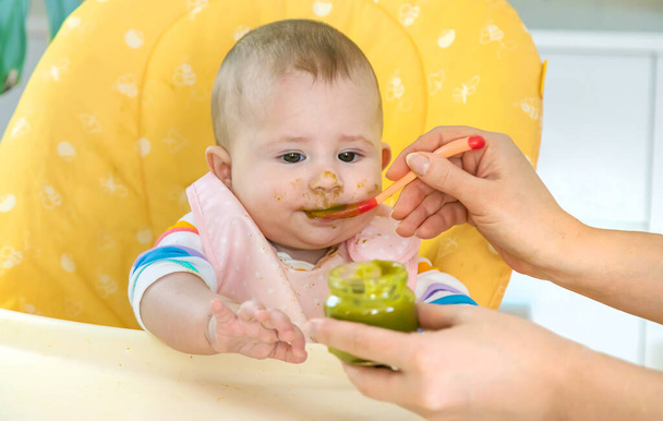 Le petit bébé mange de la purée de légumes brocoli. Concentration sélective. Les gens. - Photo, image