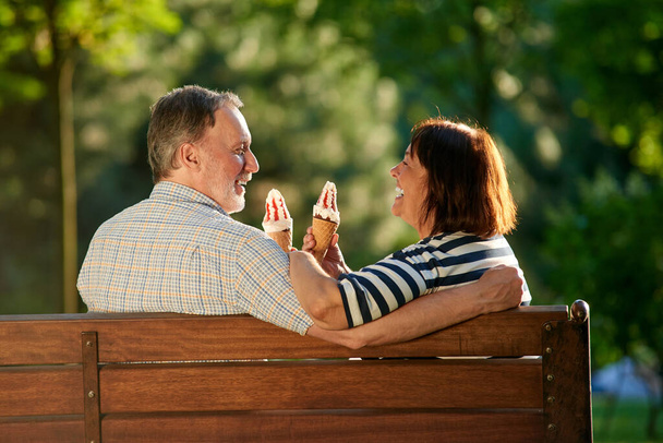 Συνταξιούχο ζευγάρι στον πάγκο του πάρκου που τρώει παγωτό.. - Φωτογραφία, εικόνα