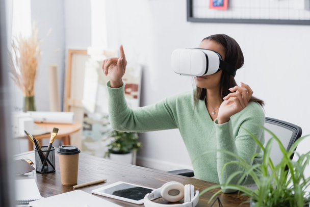 african american freelance architect gesturing while using vr headset at workplace, blurred foreground - Фото, изображение