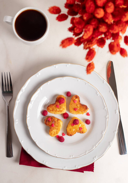 Завтрак в День Святого Валентина - чизкейки в форме сердец и красный букет.  - Фото, изображение