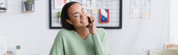 iloinen afrikkalainen amerikkalainen arkkitehti silmälaseissa puhuu matkapuhelimella katsoessaan pois, banneri - Valokuva, kuva