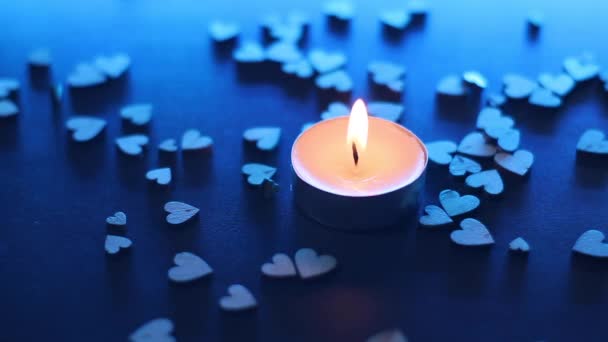 sfoukni svíčku poblíž dřevěných postav ve tvaru srdce na stole v modrém podsvícení. kouř ve zpomaleném filmu. Valentýn, Valentýn, láska, vztah, romantika. Vysoce kvalitní FullHD záběry - Záběry, video