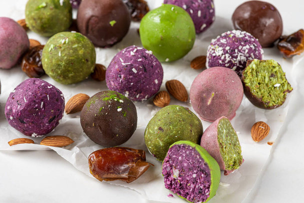 Raw vegan desserts. Energy balls. Various colorful bliss balls in chocolate glaze on white background. close up - Photo, Image