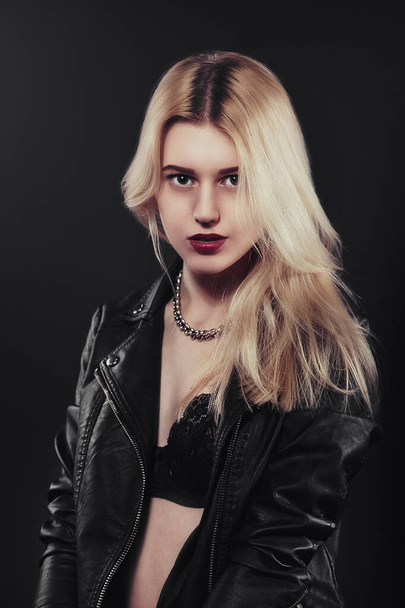 A beautiful, glamour young blond Girl in a black jacket is posing on black background - Valokuva, kuva