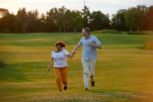 Feliz casal rindo correndo na grama. - Foto, Imagem