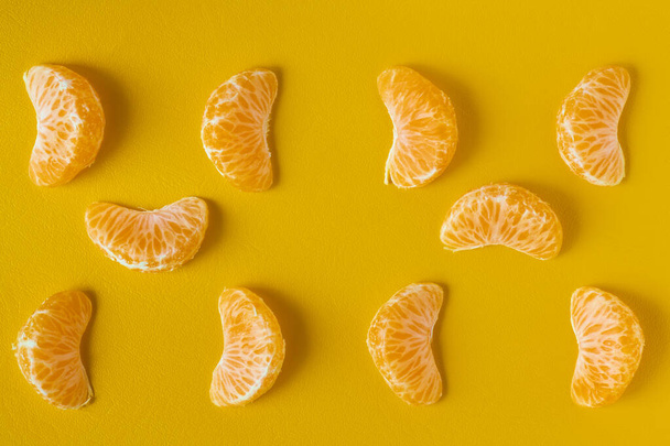 Mandarine slice shot on flat lay on yellow background. Set of ripe mandarine slice, closeup - Fotó, kép