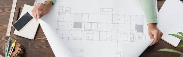vista cortada do arquiteto afro-americano perto do blueprint e smartphone com tela em branco, banner - Foto, Imagem