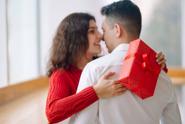Young couple with gift box hugging and celebrating Valentine's Day. Relationship, holiday,  surprise and love concept. - Fotoğraf, Görsel
