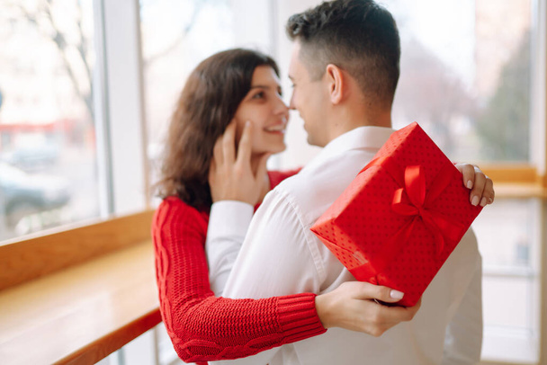 Young couple with gift box hugging and celebrating Valentine's Day. Relationship, holiday,  surprise and love concept. - Φωτογραφία, εικόνα