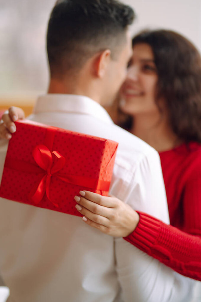 Young couple with gift box hugging and celebrating Valentine's Day. Relationship, holiday,  surprise and love concept. - Fotó, kép
