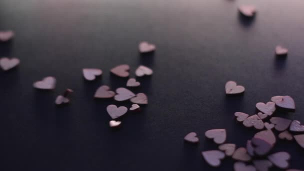 Küçük tahta kalp şekilli figürler ağır çekimde siyah masaya düşüyor. Sevgililer günü, sevgililer günü, aşk, ilişki, romantik. Yüksek kaliteli FullHD görüntüler - Video, Çekim