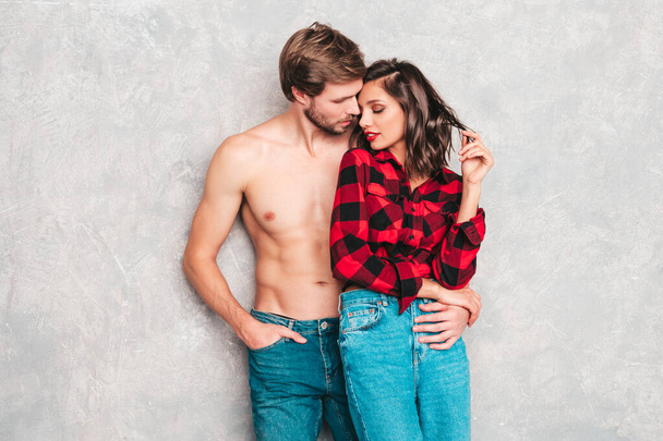 Hot beautiful woman and her handsome boyfriend. Models posing near gray wall in jeans clothes. Young passionate couple hugging before having sex. Sensual pair getting closer for kiss. Lover couple - 写真・画像