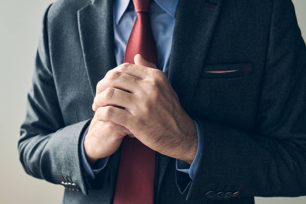 Anxious businessman wringing hands, close up with selective focus - 写真・画像