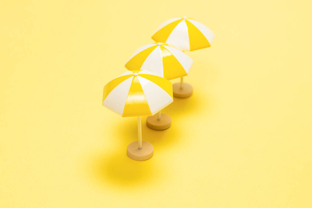 Sun lounger and yellow umbrella on a yellow background. - Foto, imagen