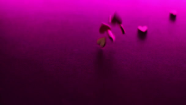 kleine herzförmige Figuren aus Holz fallen in rosafarbener Licht-Zeitlupe auf den Schreibtisch. Valentinstag, Liebe, Beziehung, Romantik. Hochwertiges FullHD-Filmmaterial - Filmmaterial, Video