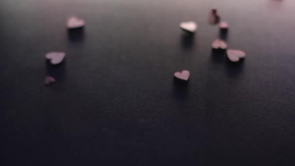 Küçük tahta kalp şekilli figürler ağır çekimde siyah masaya düşüyor. Sevgililer günü, sevgililer günü, aşk, ilişki, romantik. Yüksek kaliteli FullHD görüntüler - Video, Çekim