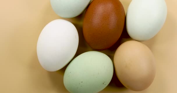 Φυσικά χρωματιστά αυγά περιστρεφόμενα σε μπεζ φόντο. - Πλάνα, βίντεο