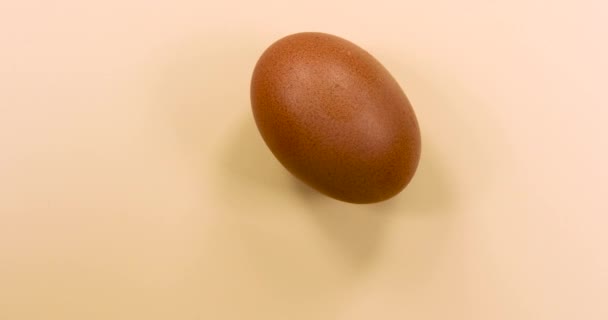 Natuurlijk gekleurd ei draaiend op een beige achtergrond.  - Video