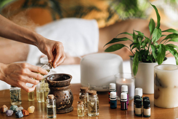 Ájurvédská aromaterapeutická masáž, ženské ruční nalévání aromatického oleje do difuzoru éterického oleje - Fotografie, Obrázek