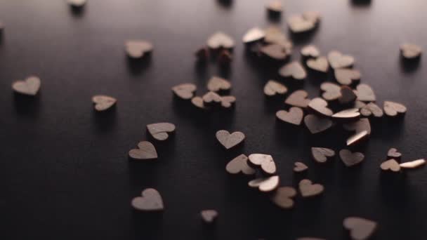 pequeñas figuras en forma de corazón de madera cayendo sobre escritorio negro en cámara lenta. San Valentín, San Valentín, amor, relación, romántico. Imágenes FullHD de alta calidad - Metraje, vídeo