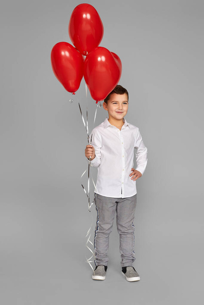 little child boy holding red heart shaped balloons - Φωτογραφία, εικόνα