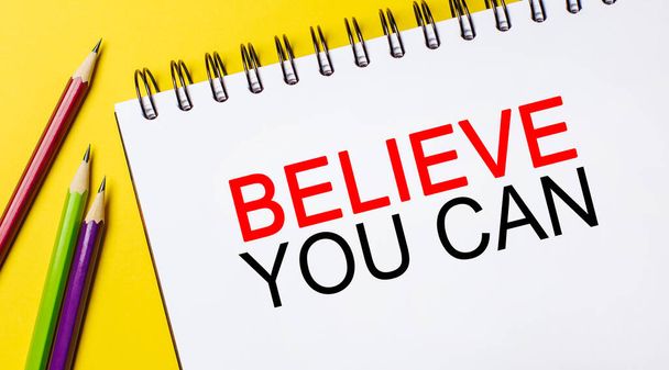 Believe you can on a white notepad with pencils on a yellow background. Business concept - Photo, image