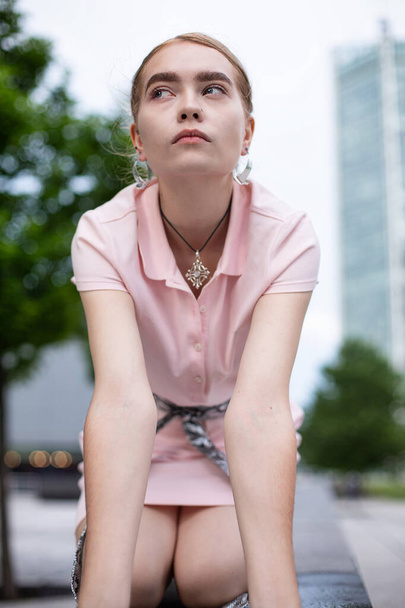 European woman with blonde hair sitting in city - Фото, зображення
