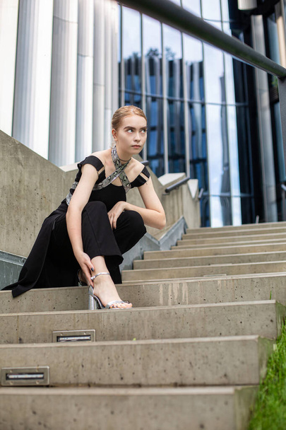 European young woman on concrete stairs near metal panels - 写真・画像