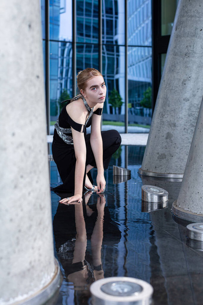 City fashion european white young woman sitting among concrete columns - Foto, Bild