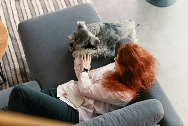 Vue du dessus de la belle jeune femme avec chien jouant à la maison - Photo, image