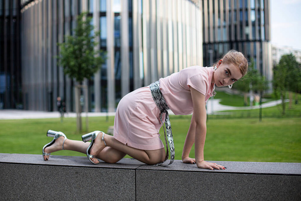 Young girl with blonde hair in city in pink dress - Foto, afbeelding