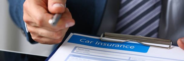Мужчина держит форму заявления о страховании автомобиля
 - Фото, изображение