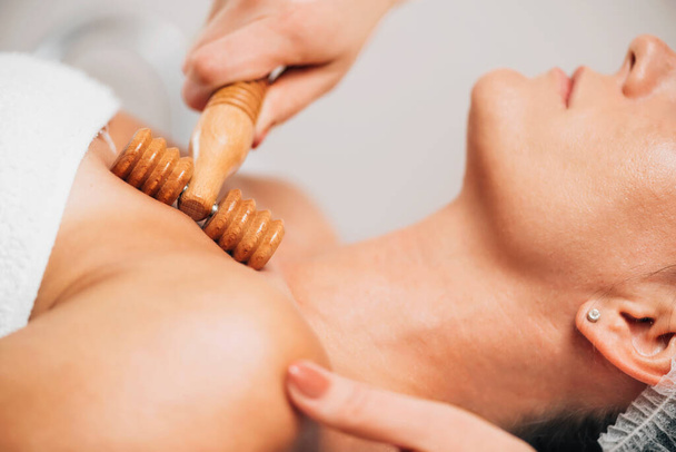 Maderotherapie Anti-Aging Massage Behandeling van Decolletage en nek van de vrouw met houten rollen - Foto, afbeelding