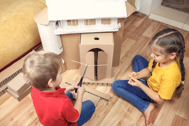 Нульові відходи домашньої активності. Діти роблять паперовий будинок з картонною коробкою після онлайн-доставки та гри разом, творчу ідею для ізоляції будинку. Уявні навички та концепція творчого мислення
 - Фото, зображення