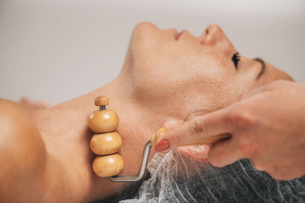 Massage anti-âge du cou et de la poitrine avec masseur à rouleaux en bois - Photo, image