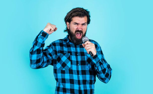 hipster with long hair and moustache sing song. male in karaoke. music and vocal concept. bearded man in checkered shirt with microphone. casual guy country music singer - Fotó, kép