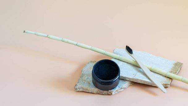 Bir kutuda organik kömür tozu ve doğal taşlarda bambu diş fırçası ve diş beyazlatmak için doğal bej arka plan. Diş bakımı, sağlık konseptleri.. - Fotoğraf, Görsel